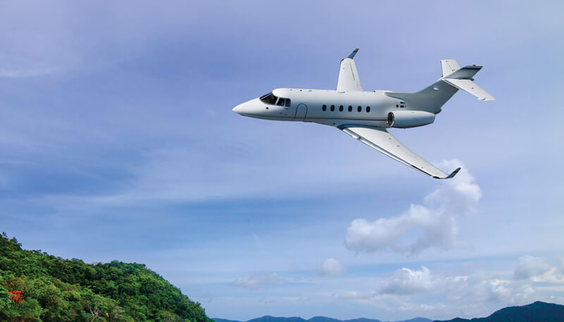 A luxury private jet flying over a tropical beach booked by Dela World Charter.