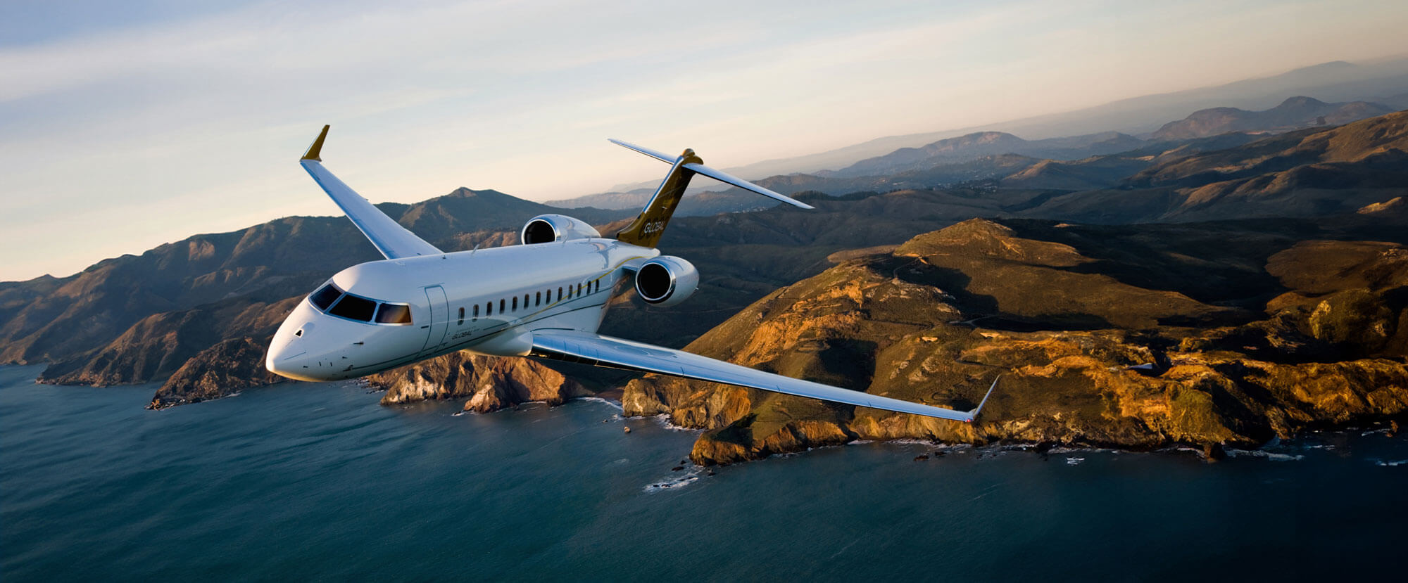 A luxury private jet flying over the sea operated by Dela World Charter.