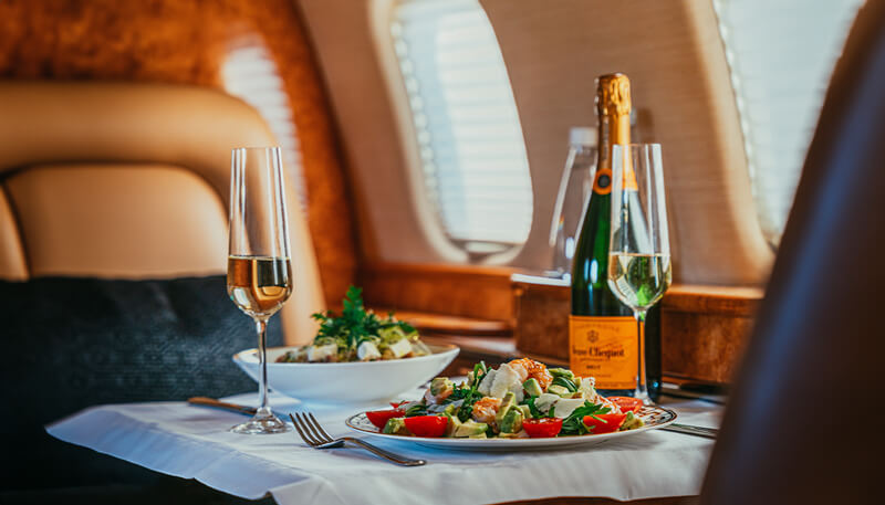 Luxury in-flight catering and Champagne aboard a private jet booked by Dela World Charter.