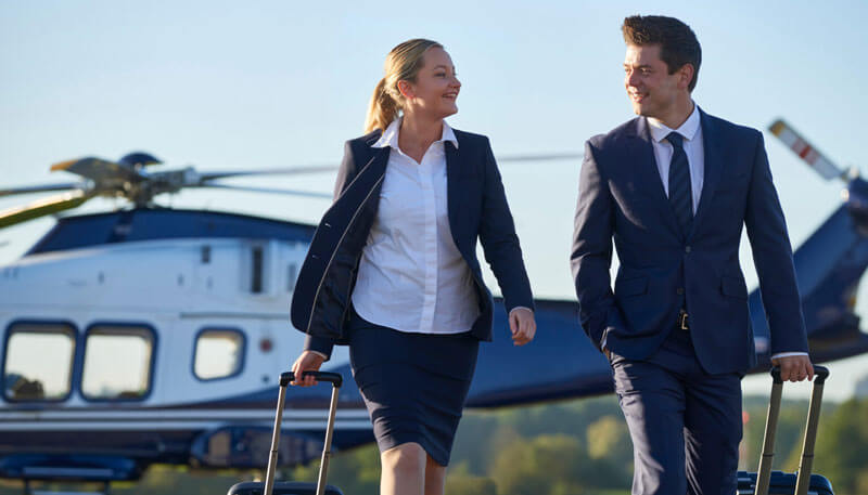 2 business professionals walking on a runway from a helicopter booked by Dela World Charter.
